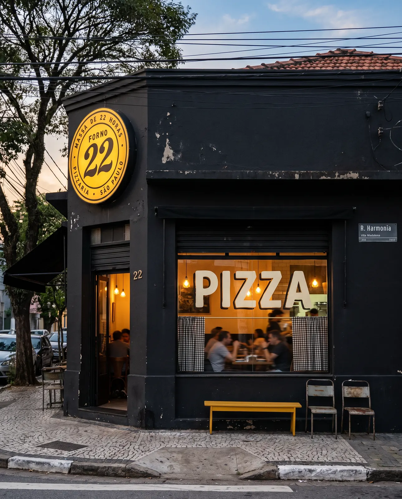 Fachada carvão da Forno 22, com o selo mostarda iluminado na esquina da Rua Harmonia